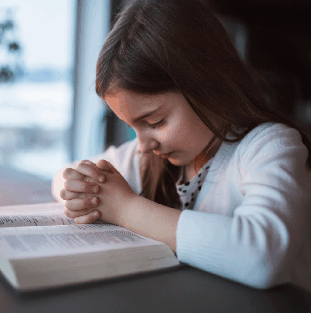 A small girl praying at home.